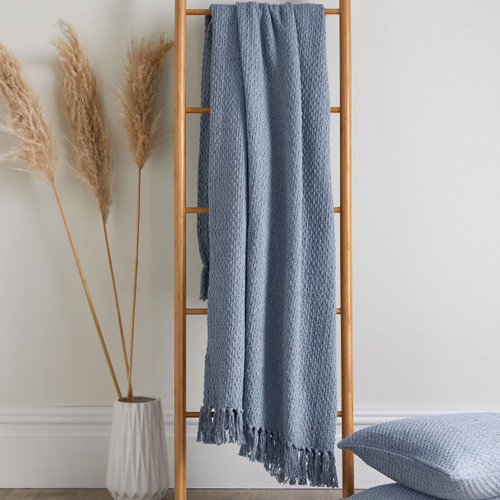 A blue throw hanging off a ladder next to some pampas grass