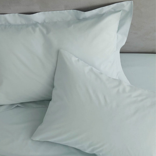 Two duck egg blue pillows on a bed with soft lighting.