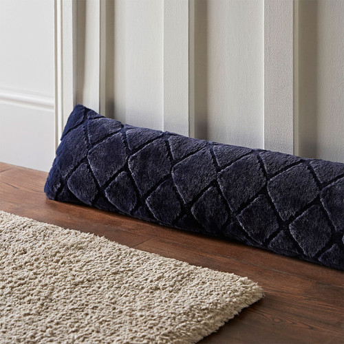 Navy blue diamond-patterned draught excluder by a door, with beige rug on wooden floor.