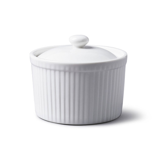 A white porcelain ramekin with a lid on a plain background.