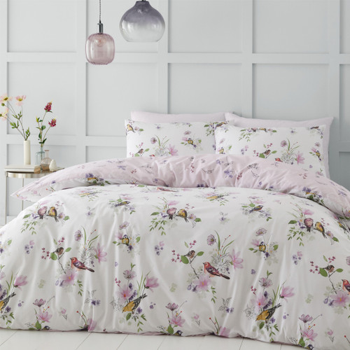 A view of a bed with a reversible white bedding set with a floral bird bedding design