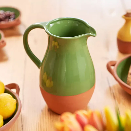 A green and brown serving jug on a wooden table