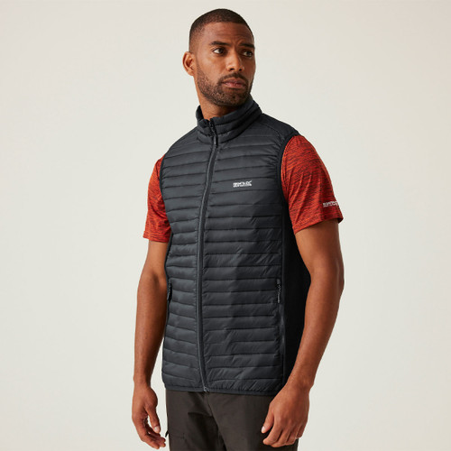 A man wearing a black quilted gilet over a red t-shirt.