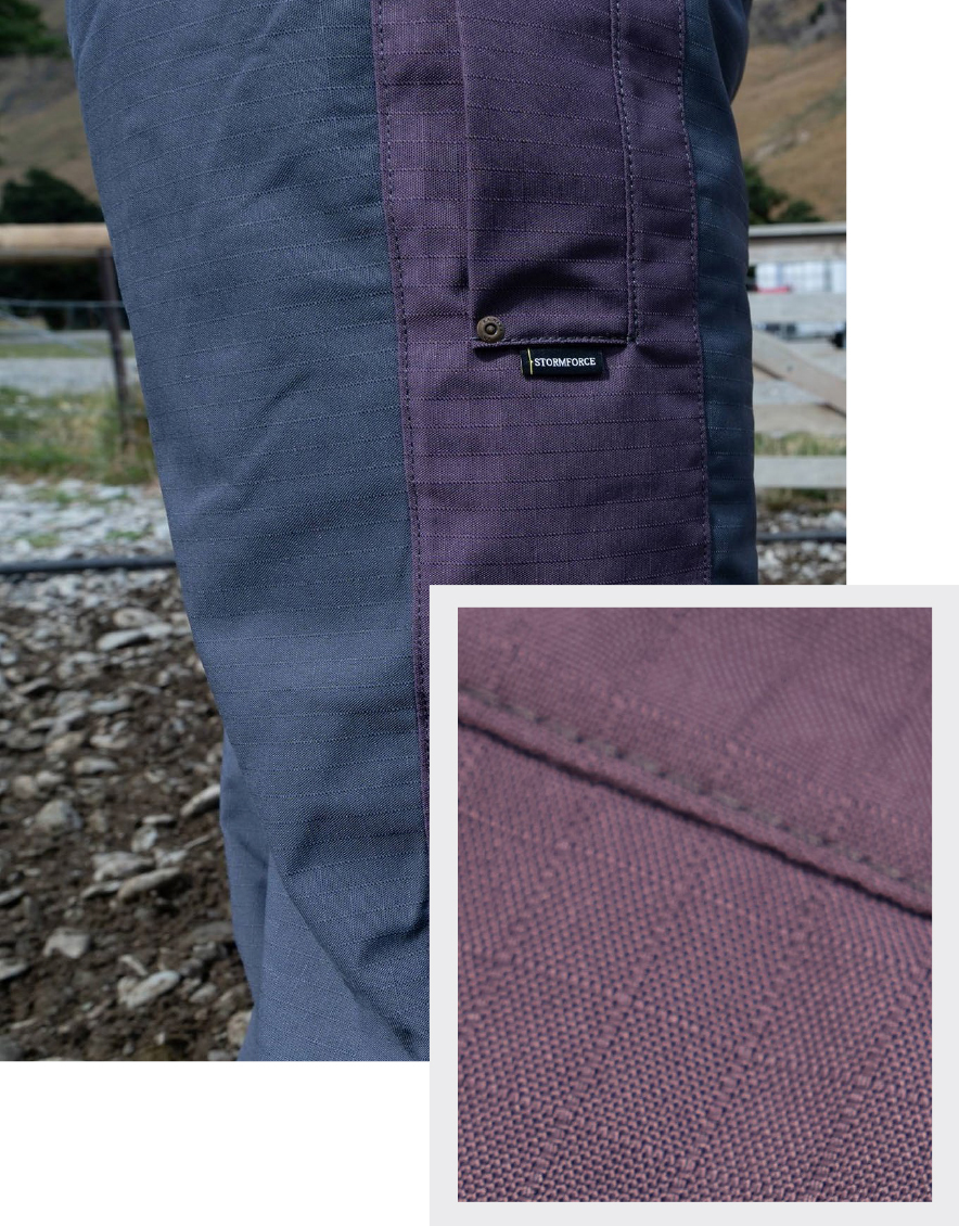 Close-up of a two-toned fabric pants leg outdoors. The left is dark gray, and the right is purple with a visible label. Inset shows detailed purple texture.