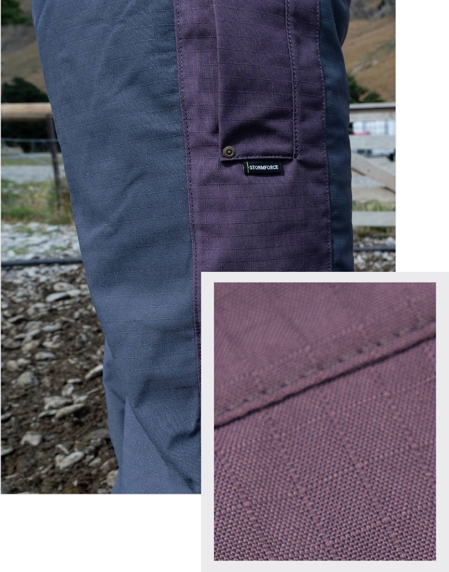 Close-up of a two-toned fabric pants leg outdoors. The left is dark gray, and the right is purple with a visible label. Inset shows detailed purple texture.