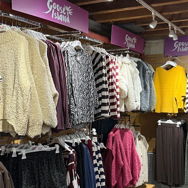 A range of jumpers and tops hanging from clothing rails.