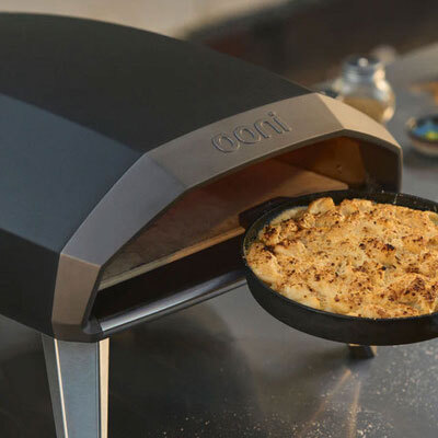 A close up of a dish going into an ooni pizza oven