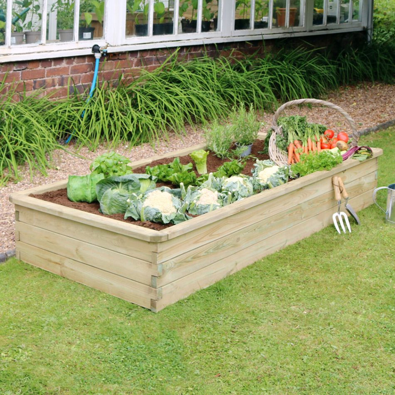 A view of a large wooden planter filled with vegetables in a garden