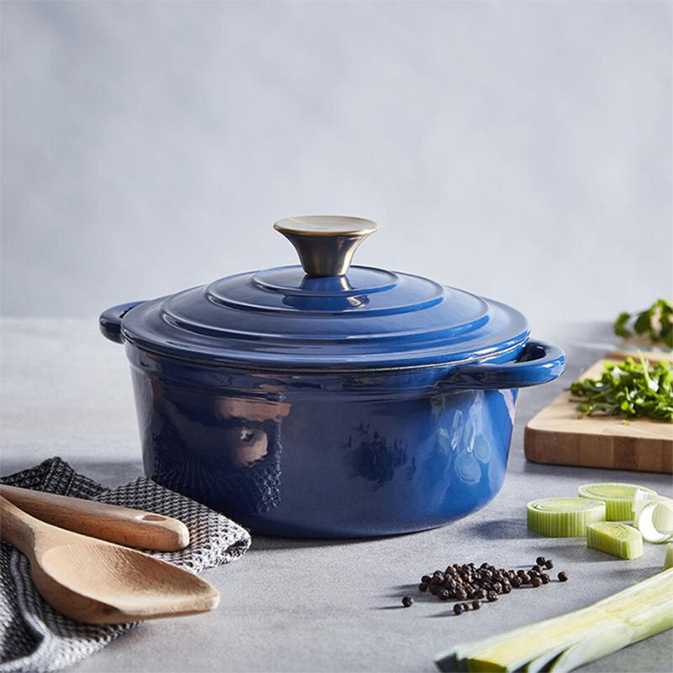 A view of a dark blue casserole dish pn a table surrounded by cooking ingredients 