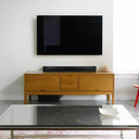 Csc Electronics 4K UHD Sound Bar WiFi Surveillance Camera with Wireless Streaming, TV setup with a large flat-screen TV mounted on the wall above a wooden entertainment console in a modern living room.