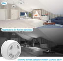 Fuvision Battery Powered Dummy Smoke Detector WiFi Night Vision Security Camera, bottom view, showing lens for home security, motion activation, 180 days battery life, night vision, SD card slot, and remote internet access, installed in a living room.