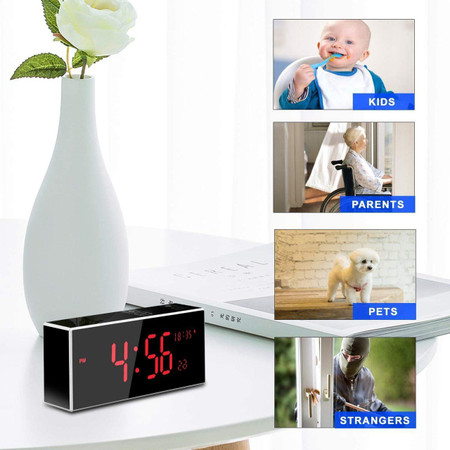 Gio Enterprises Wi Fi Clock, a digital clock on a desk with a black and red display showing the time 4:56, next to a white vase with a white flower. Inset images show the Wi Fi surveillance camera with 33FT night vision, support for motion detection, and a 160-degree angle, used for monitoring kids, parents, pets, and strangers.