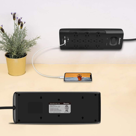 CSC Electronics WiFi Surge Protector USB Tap 4K UHD Security Camera with Live View WiFi and DVR, black power strip with multiple outlets, connected to a smartphone and a decorative plant on a desk.