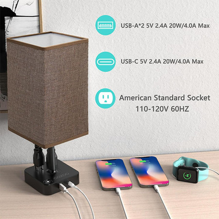 Csc Electronics UHD 4K WiFi Lamp USB Charging Station with Bedside Security Camera and Live View DVR, scene showing a modern lamp with USB charging ports connected to smartphones, and a smart watch, on a wooden surface.