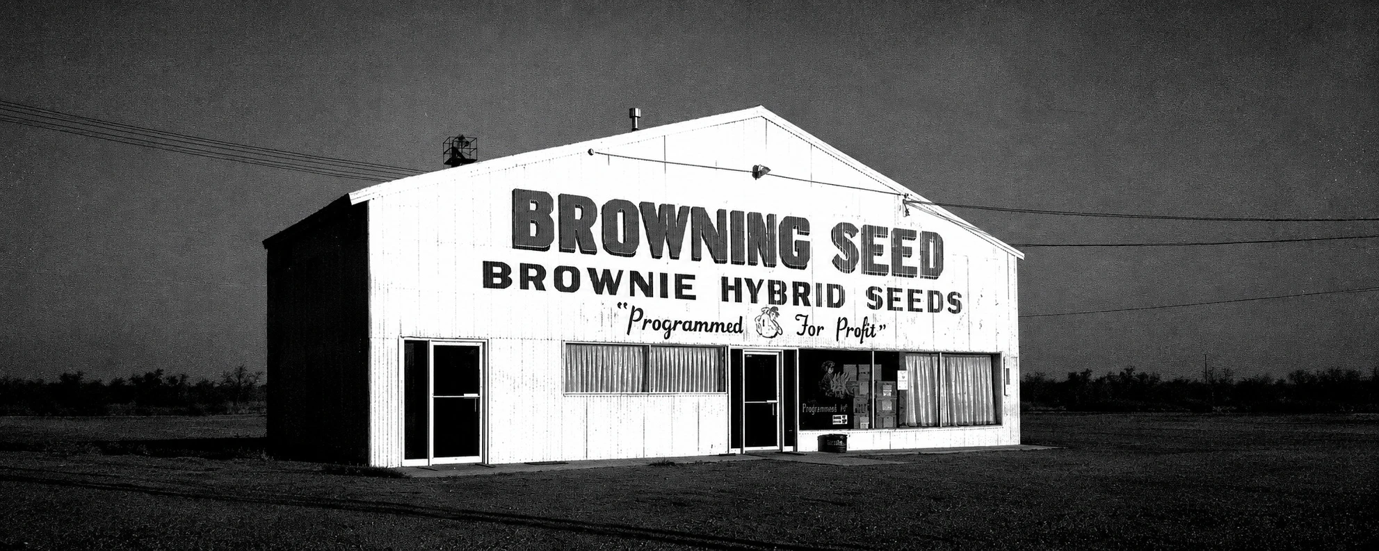 Black-and-white photo of the original Browning Seed plant, painted "Browning Seed, Brownie Hybrid Seeds, Programmed for Profit"