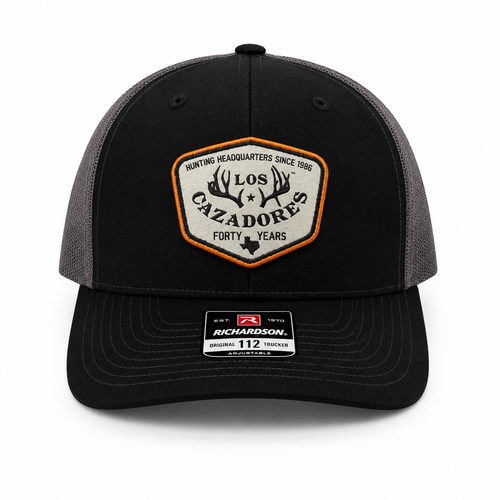 Whitebox image of Los Cazadores trucker cap featuring a black front panel, curved brim, gray mesh back, and commemorative “Forty Years” front patch.