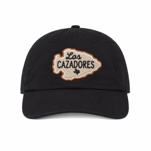 Front view of the Los Cazadores black cap with corrected cream arrowhead logo patch on a clean white background.