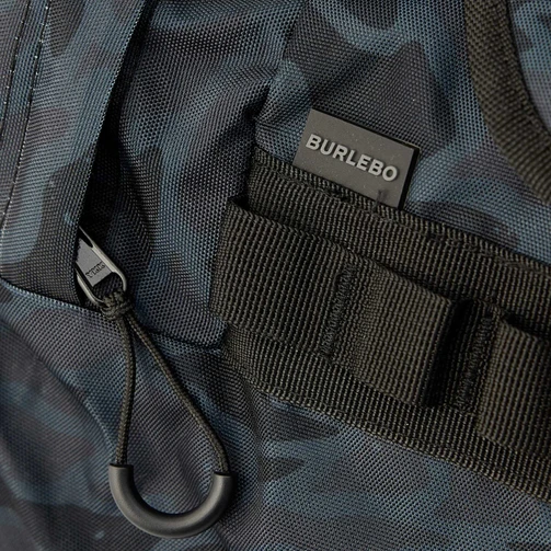 Close-up of the Burlebo logo tab and zipper pull on the black camo duffle bag