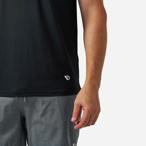Close-up of the small Flying B logo on the hem of the Burlebo black performance tee