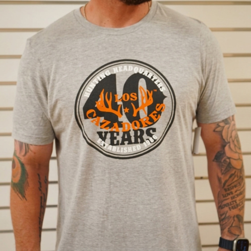Front view of the Los Cazadores 40 Years Short Sleeve Tee in heather gray featuring the commemorative 40 Years Hunting Headquarters graphic on a male model.