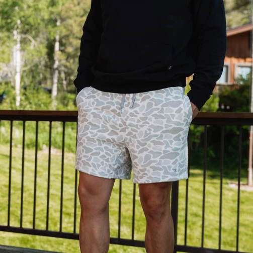Man wearing Burlebo vintage washed shorts in classic deer camo on an outdoor deck