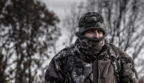 Hunter wearing the Pnuma Highpoint Beanie and neck gaiter in Caza OV camo outdoors in winter
