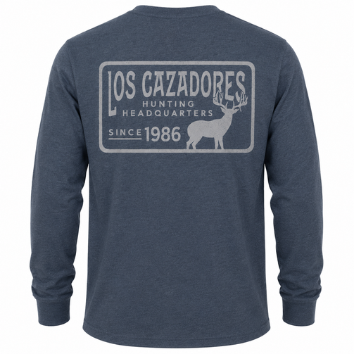 Back view of a Los Cazadores adult long-sleeve performance shirt displayed on an invisible ghost mannequin against a white background. The heather slate-blue shirt features a large tonal gray Los Cazadores graphic centered across the upper back with "LOS CAZADORES," "Hunting Headquarters," "Since 1986," and a whitetail deer silhouette enclosed within a rectangular border. The long-sleeve construction and heathered fabric texture are showcased in a clean ecommerce-style product image.