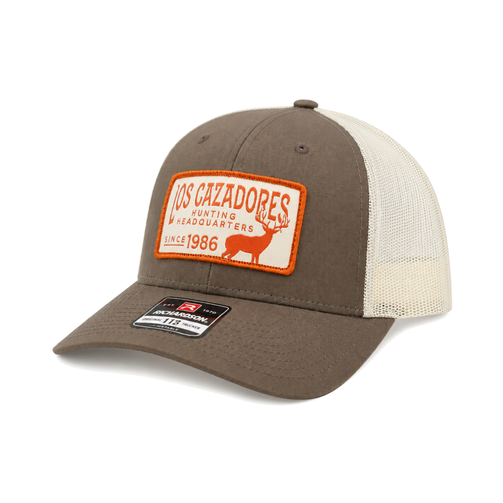 Angled-left view of the Los Cazadores taupe and cream mesh trucker hat featuring the orange Hunting Headquarters patch.