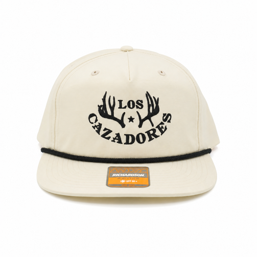 Front view of an ivory Los Cazadores rope hat with black embroidered logo and flat brim on a white background.