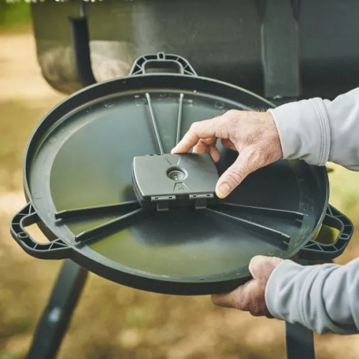 Close-up installation photo of the Moultrie Universal Feed Hub Unit being positioned inside a feeder lid.