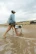 lifestyle image of woman carrying white turtlebox cub speaker on the beach