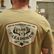 close up view of the back side of an individual wearing the los cazadores special edition 40th year badge short sleeve tee.