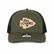 Front view of the Los Cazadores olive and black trucker cap with arrowhead patch and brim sticker on a clean white background.