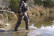 Hunter wearing the Pnuma Torrent Pant in Caza OV camo wading across a creek