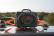 Green Turtlebox speaker strapped to a vehicle roof with orange Turtlebox tie-down straps