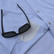 Close-up of sunglasses in the built-in sunglasses holder on a light blue Poncho Western pearl snap shirt