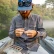 Angler in a cap tying on a fly from a tackle box aboard a boat while wearing a grey Poncho Western long sleeve pearl snap shirt