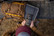 Hunter installing the Stealth Revolver Pro 2.0 cellular game camera with a solar panel for outdoor field monitoring.