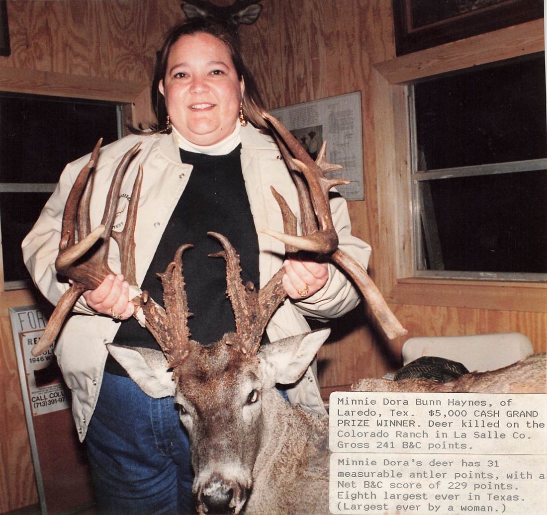 Minnie Dora Bunn Haynes holds the massive antlers of her grand prize winning buck inside a wood-paneled room
