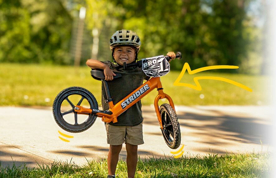 A child easily lifts the Strider 12 Pro with a smile on their face