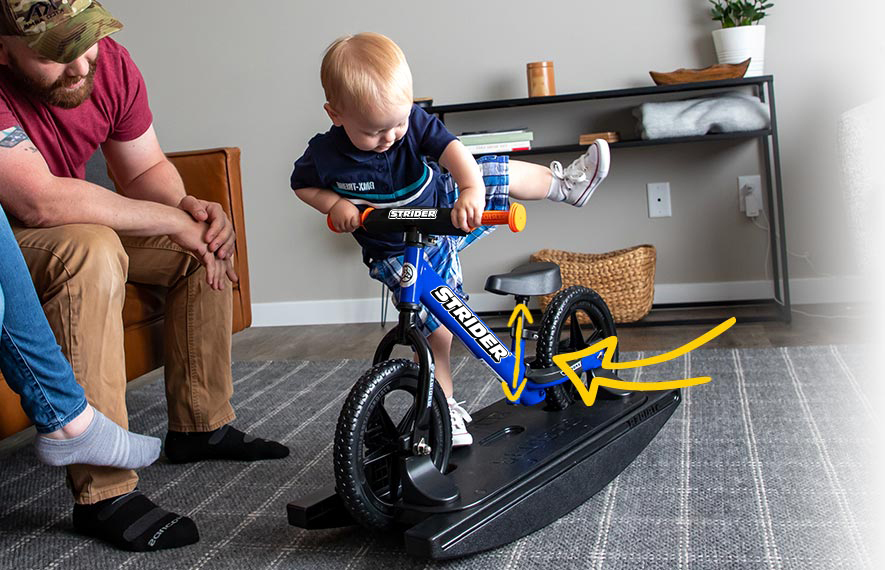 small child brings leg up and over the saddle of a Strider Rocking Bike