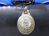 A commemorative medal decorated with a ribbon, celebrating the 60th birthday anniversary of Her Majesty Queen Sirikit, 2004, "female model"