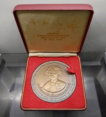 A commemorative coin for Her Majesty Queen Sri Savangavadhana's 90th birthday, made of blackened copper, 7 cm in diameter, minted in 1990 (B.E. 2533), with original box.