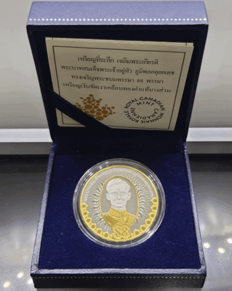 A commemorative coin celebrating the 88th birthday of King Rama IX, made of polished silver with partial plating of real gold, complete with original box and all accessories.
