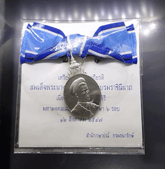 A commemorative medal decorated with a ribbon, celebrating the 60th birthday anniversary of Her Majesty Queen Sirikit, 2004, "female model"