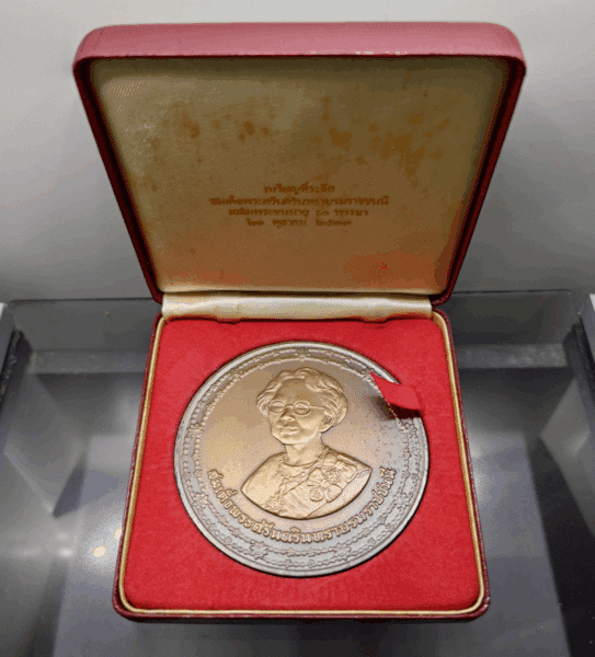 A commemorative coin for Her Majesty Queen Sri Savangavadhana's 90th birthday, made of blackened copper, 7 cm in diameter, minted in 1990 (B.E. 2533), with original box.