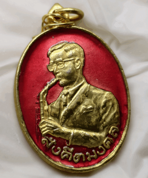Auspicious musical medal with the royal inscription "The King plays music" on the back, made of gold-plated brass with red enamel, celebrating the 21st anniversary of the Music Association of Thailand, 1987.