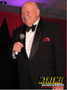 "Don Rickles impersonator roasting the audience at a corporate event with his classic humor"