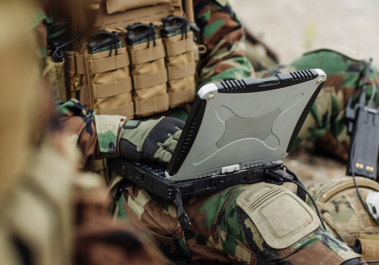 soldier wearing gloves works on laptop