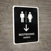 Restrooms With Down Arrow Black Bilingual Spanish Portrait - Wall Sign